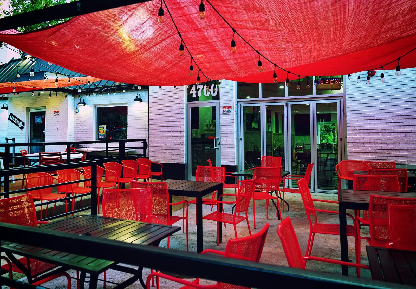 Tables and chairs on a restaurant patio under a shade sail. The photo was not taken in Daytona Beach.