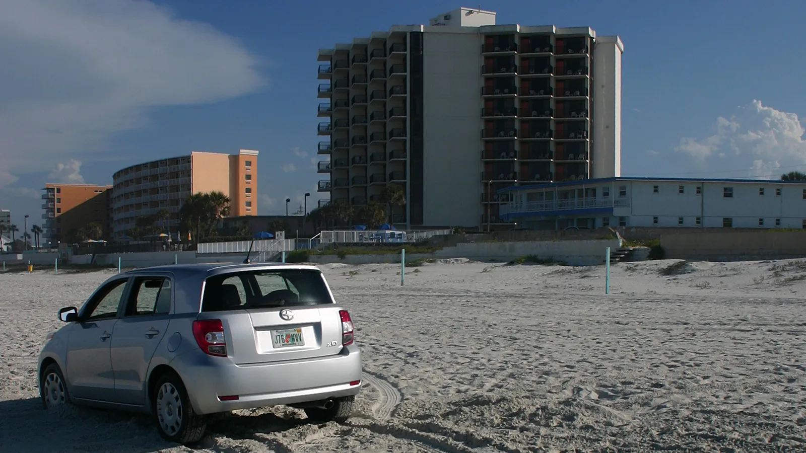 A car parked on the sand below the beachside hotels in Daytona Beach.