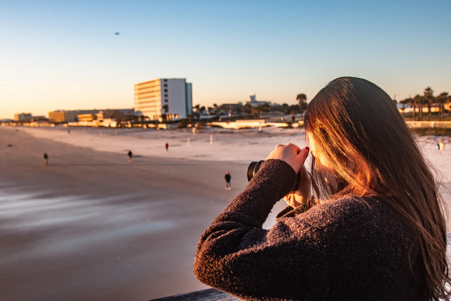 A visitor photographs the beach in early morning light from the Daytona Beach Pier.
